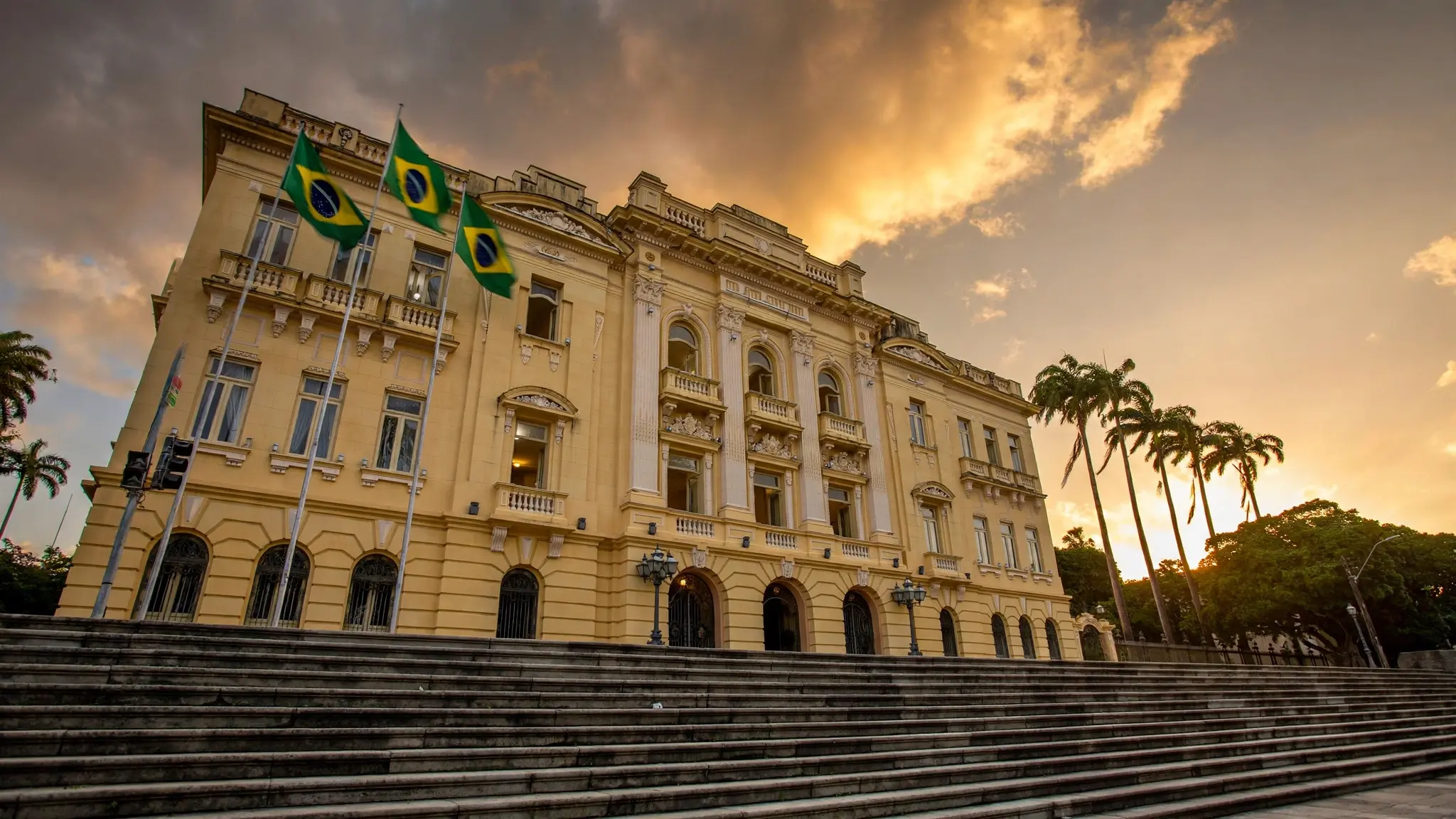 Assembleia Legislativa de Pernambuco ao entardecer com bandeiras do Brasil tremulando
